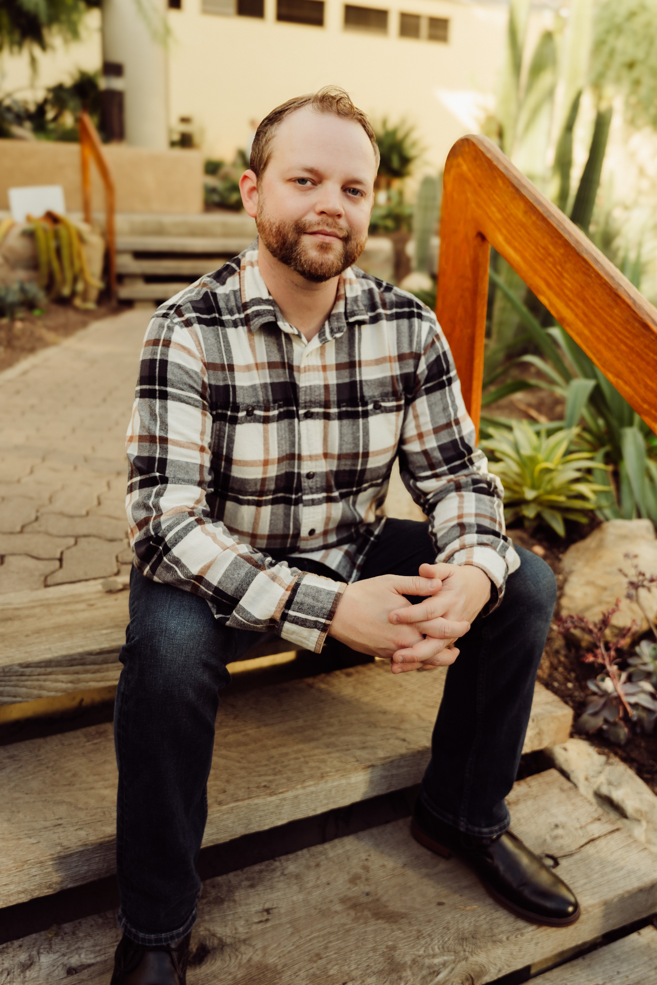 Portrait of Brennan Doud seated on wooden steps in a garden
